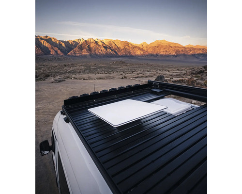 Dachgepäckträger auf einem Fahrzeug mit Tisch und Behälter vor Bergkulisse