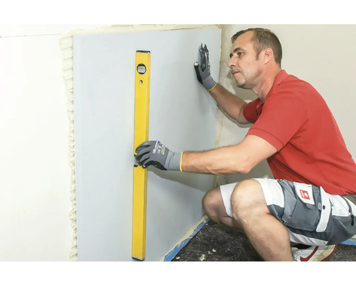 Handwerker richtet Trockenbauwand mit Wasserwaage aus
