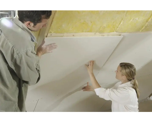 Zwei Personen befestigen eine Gipskartonplatte an einer Decke