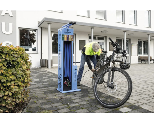 Fahrradreparaturstation mit Person, die einen Reifen aufpumpt