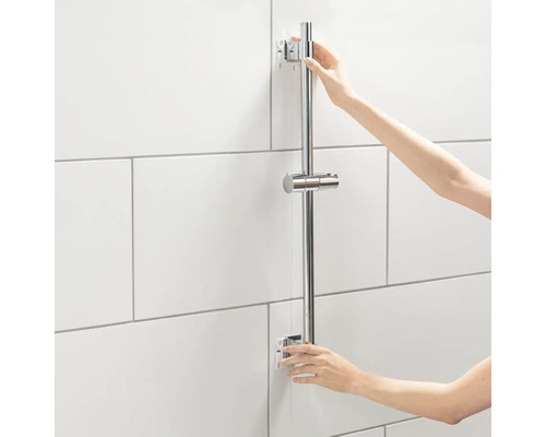 Person montiert eine Duschstange an einer gefliesten Wand.