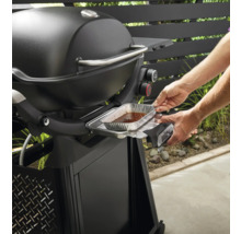 Weber Grill mit Person, die eine Tropfschale einsetzt