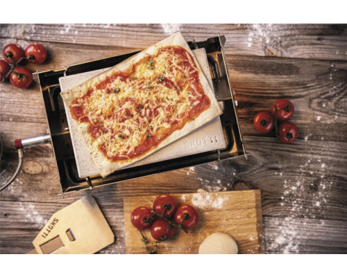 Pizzaofen mit Pizza, Pizzaschieber, Tomaten und Teig auf einem Holztisch
