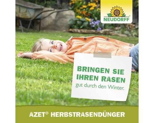 Mädchen liegt auf Rasen mit Schild: Bringen Sie Ihren Rasen gut durch den Winter. Azet Herbstrasendünger
