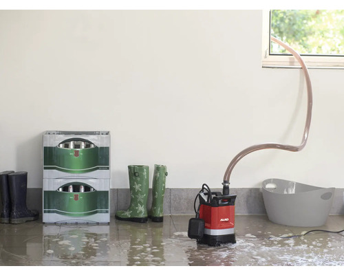 Raumszene mit Tauchpumpe, Getränkekisten und Gummistiefeln im überfluteten Raum