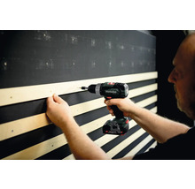 Handwerker befestigt Holzlatte mit Akku-Bohrschrauber an Wand