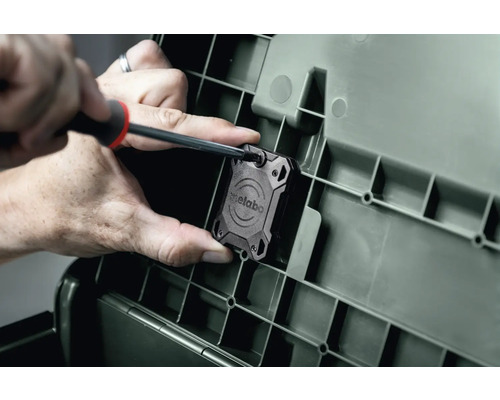 Person befestigt Metabo Lautsprecher mit Schraubendreher an Werkzeugkoffer