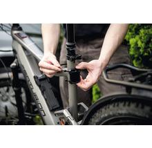 Nahaufnahme eines Mannes, der ein Fahrradzubehör an einem Fahrrad befestigt