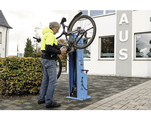 Mann repariert Fahrrad an öffentlicher Fahrradreparaturstation
