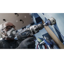 Handwerker bohrt mit einer Bohrmaschine ein Loch in eine geflieste Wand
