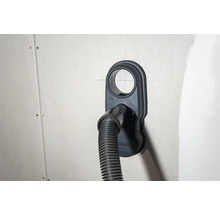 Staubsaugeranschlussdose mit angeschlossenem Staubsaugerschlauch an einer Wand