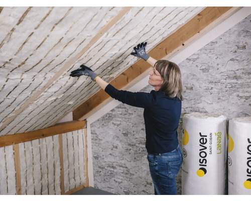 Dachdämmung mit Frau, die Dämmwolle anbringt, Holzsparren und Rollen der Marke Isover