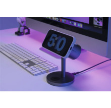 Smartphone auf Ladestation neben Computertastatur und Monitor.