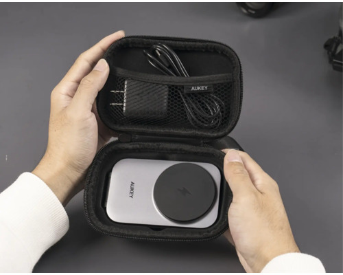 Person hält offenes Aukey-Ladegerät-Etui mit Ladegerät, Kabel und drahtloser Ladestation