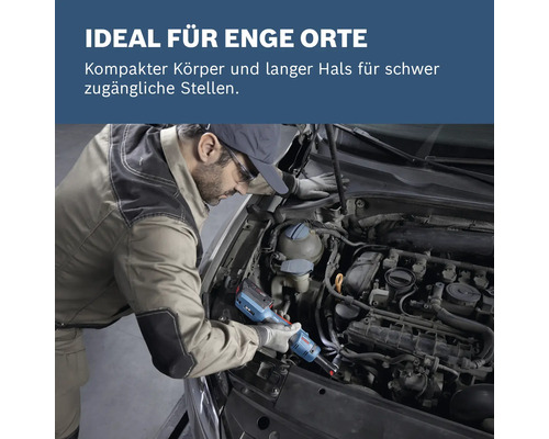 Ein Mann repariert mit einem Schraubendreher einen Automotor an einem schwer zugänglichen Ort.