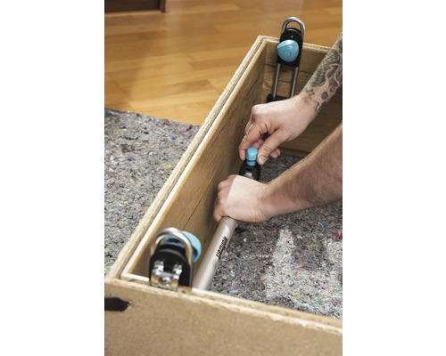 Mann befestigt Wolfcraft Montagewinkel in Holzkiste