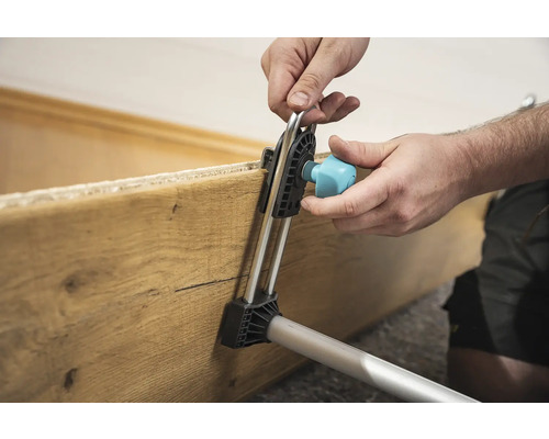 Anwender befestigt ein Holzbrett mit einem Montagewerkzeug.