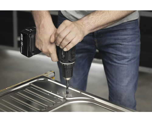 Handwerker bohrt mit einer Bohrmaschine ein Loch in ein Spülbecken