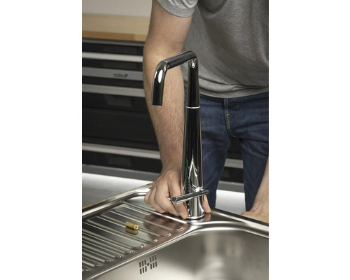 Ein Mann installiert einen Wasserhahn in einer Spüle.