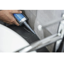 Eine Person trägt Silikon auf eine Marmoroberfläche auf.