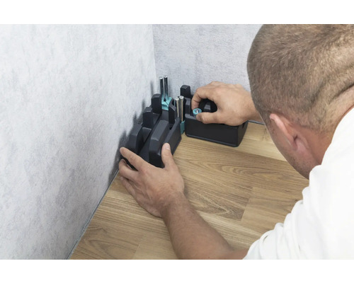 Eine Gehrungslade wird an einer Ecke auf einem Holzboden befestigt.