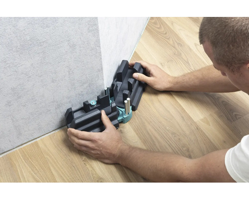 Person verwendet eine Schneidlade zum Schneiden von Sockelleisten.