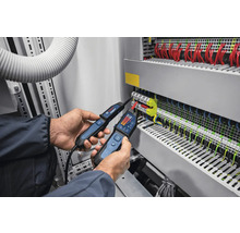 Ein Elektriker verwendet zwei Spannungsprüfer an einem Schaltschrank zur elektrischen Messung.