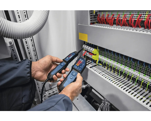 Ein Elektriker verwendet zwei Spannungsprüfer an einem Schaltschrank zur elektrischen Messung.