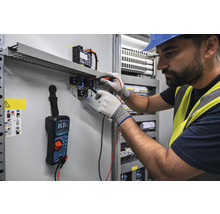 Elektriker misst Spannung an Schalttafel mit Multimeter