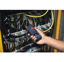 Ein Elektriker verwendet ein Bosch-Strommesszange an einer elektrischen Anlage zur Strommessung.