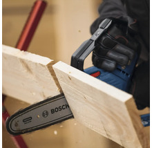 Eine Person sägt mit einer Akku-Kettensäge ein Holzbrett. Bosch Logo.