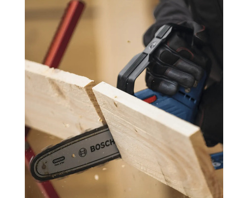 Eine Person sägt mit einer Akku-Kettensäge ein Holzbrett. Bosch Logo.