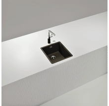 Dunkles Küchenspülbecken mit Wasserhahn auf einer weißen Arbeitsplatte.