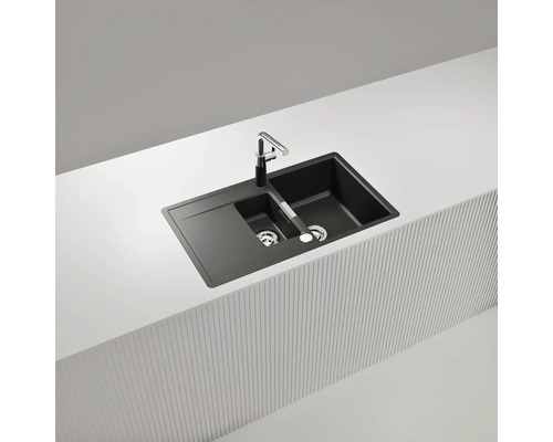 Schwarze Doppelspüle mit Abtropffläche und Armatur auf einer Küchenarbeitsplatte.