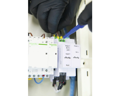Ein Elektriker arbeitet an einer elektrischen Installation mit Produkten von Schneider Electric und Shelly.