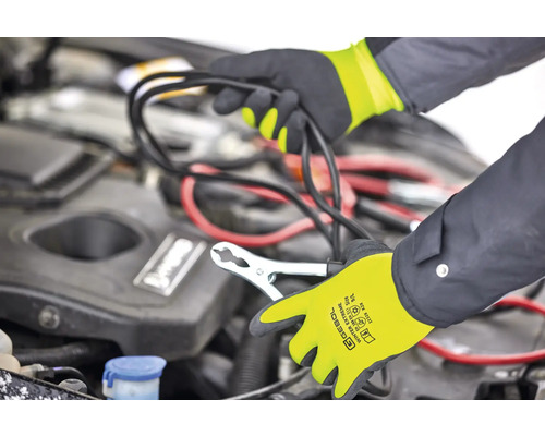 Eine Person schließt mit Überbrückungskabeln eine Autobatterie an, wobei sie Handschuhe trägt.