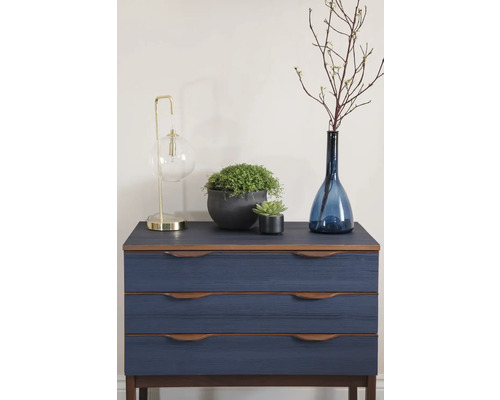 Kommode mit drei Schubladen und dekorativen Gegenständen wie Lampe, Pflanzen und Vase.
