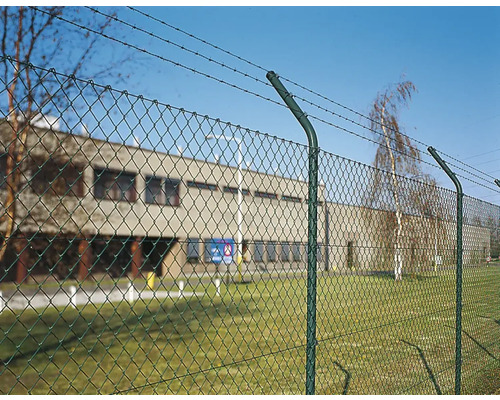 Drahtzaun mit Stacheldraht vor einem Gebäude