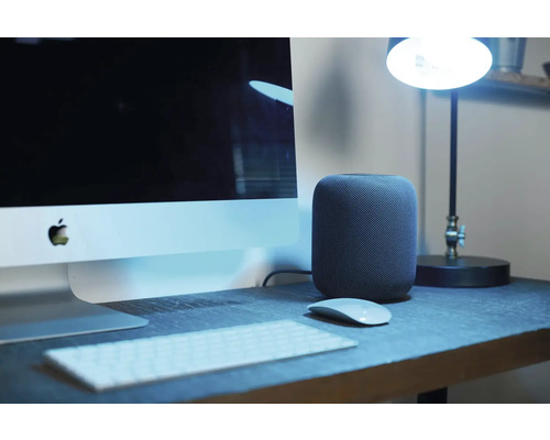 Schreibtisch mit Computer, Lautsprecher, Tastatur, Maus und Lampe