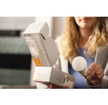 Frau hält intelligente Glühbirne und Verpackung.