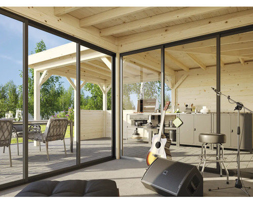 Helle Holzhütte mit Schiebetüren, Blick auf eine Terrasse mit Grillplatz und Sitzgelegenheiten.
