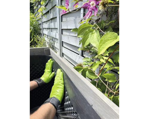 Person mit Gartenhandschuhen montiert einen Hochbeet Bausatz im Garten