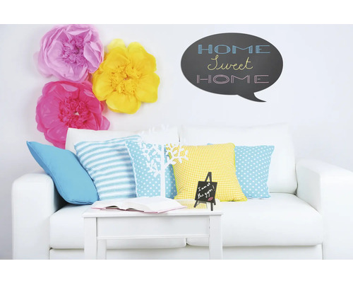 Wohnzimmer mit weißem Sofa, Kissen, Tisch, Dekoration und Wandtattoo