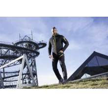 Mann in Outdoor-Bekleidung mit Jacke und Hose vor Industriekulisse