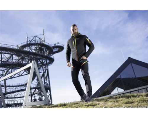 Mann in Funktionskleidung mit Jacke und Hose im Outdoor-Bereich