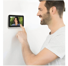 Ein Mann bedient eine Türsprechanlage mit Display.