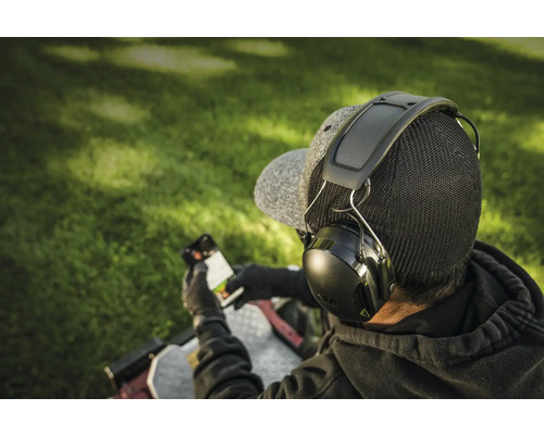 Person mit Kapselgehörschutz und Smartphone im Freien