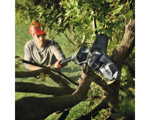 Mann sägt Ast mit einer Akku-Kettensäge von Husqvarna