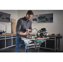 Mann arbeitet mit einem Multifunktionswerkzeug an einem Werkstück auf einer Wolfcraft Werkbank in einer Werkstatt.