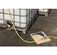 Szene mit IBC-Containern, einer Bohrmaschine und einer Schlauchpumpe auf einem Brett.